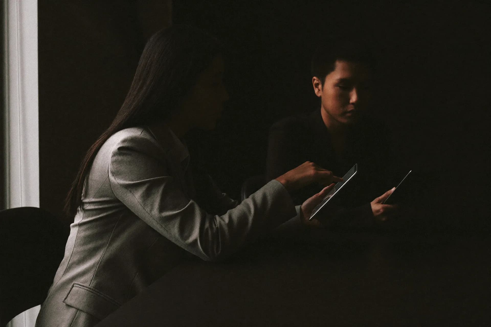 Two colleagues side by side at a table, working through something on a tablet